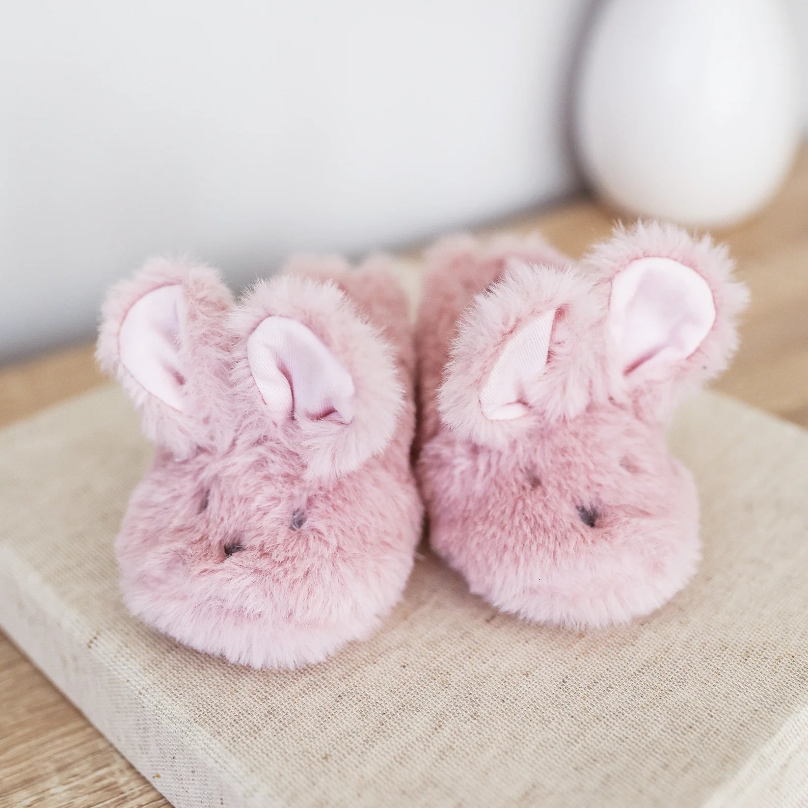 Alimrose Luxe Bunny Booties in petal pink displayed on a neutral fabric surface, front angle.