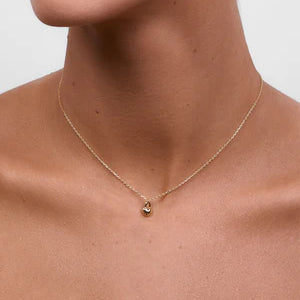 A model wearing the delicate gold chain necklace with a small heart-shaped lock pendant, sitting just above the collarbone.