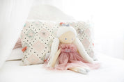 Alimrose Penelope Princess doll 50cm wearing sparkle blush tulle dress and silver crown, sitting on a bed with decorative pillow.