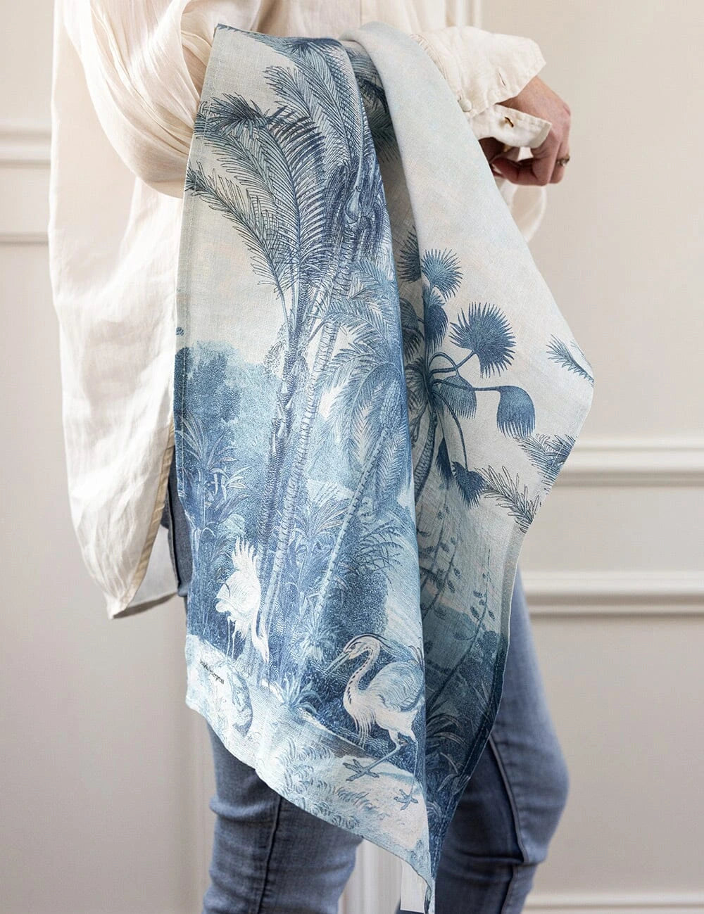 Bespoke Letterpress Subcontinent Linen Tea Towel with tropical palm and bird print, draped over arm
