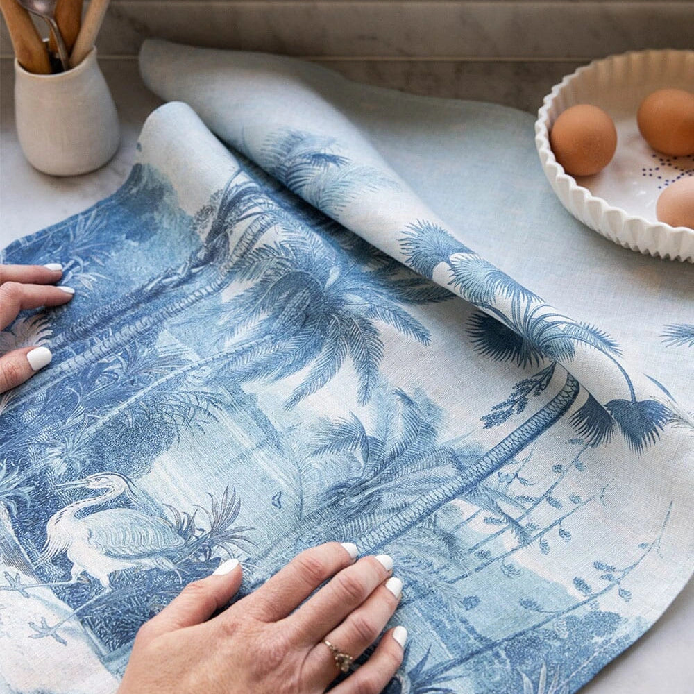 Bespoke Letterpress Subcontinent Linen Tea Towel in blue palm and bird design on kitchen counter
