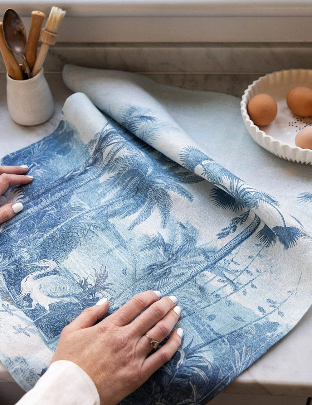 Bespoke Letterpress Subcontinent Linen Tea Towel in blue palm and bird design on kitchen counter