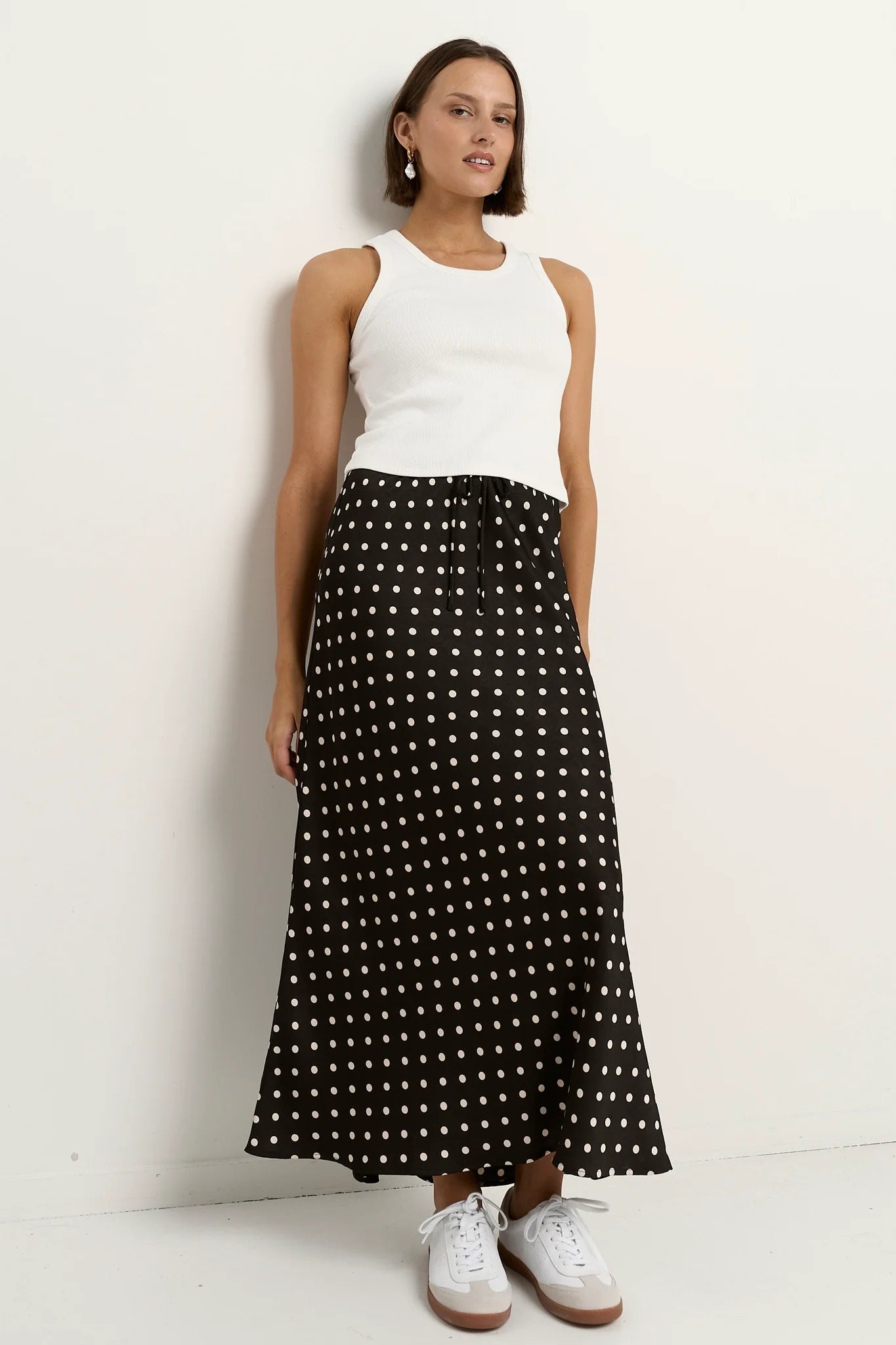 Black white polka dot satin maxi skirt styled with white tank top casual chic outfit bias cut silhouette comfortable elastic waist timeless wardrobe essential