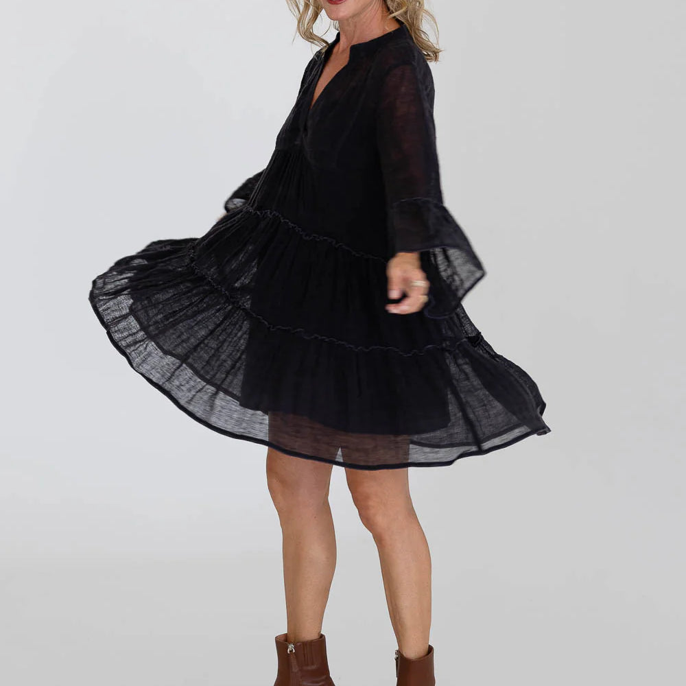 Model showcasing side view of EADIE Como Linen Dress Midnight with flared sleeves and layered design.