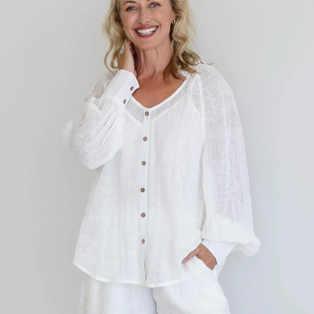 Model standing in EADIE Mika Linen Off White Blouse and shorts, hands in pockets, showcasing lightweight fabric.
