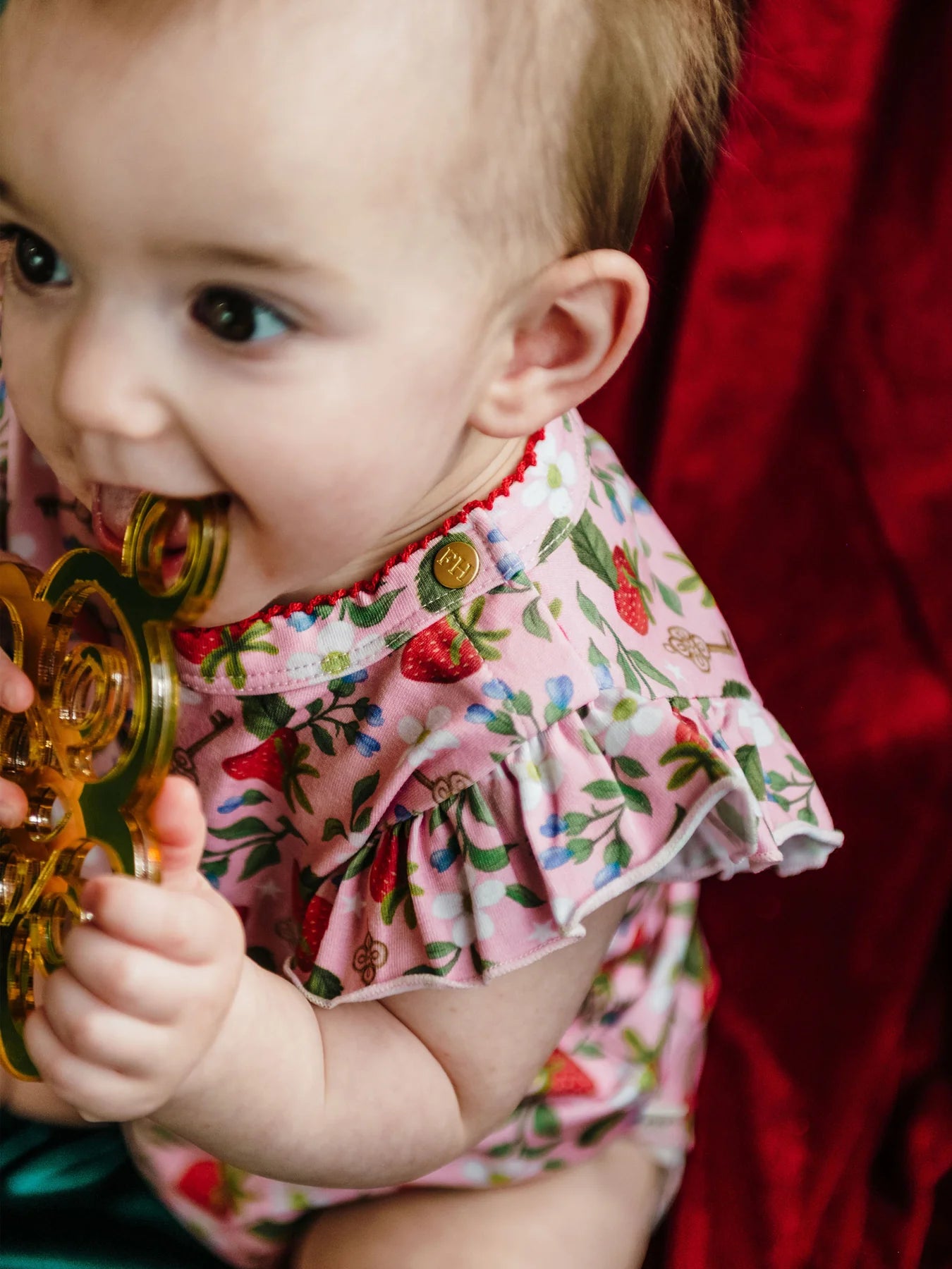 Close-up of Fleur Harris Hearts Floral Bijou Bodysuit with frilled sleeves, soft cotton fabric, and signature FH button detail.