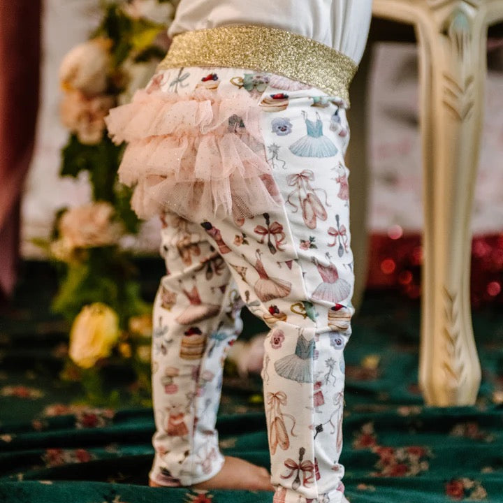 Close up of toddler in patterned leggings with gold waistband and layered pink tulle frill on back