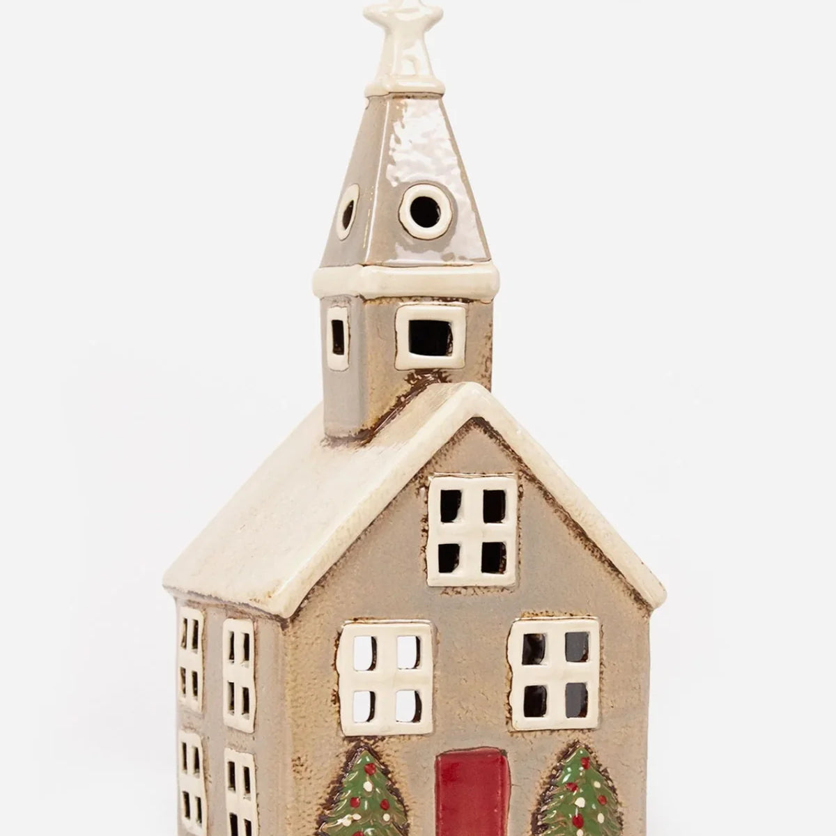 Beige ceramic tea light church with red door, white roof, and potted Christmas trees by the entrance