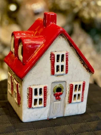Ceramic cottage in cream with red roof and shutters, featuring festive holiday wreath on the door
