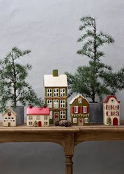 Display of French Country Alsace ceramic tea light cottages, including cream cottage with red shutters and red roof, styled with small Christmas trees