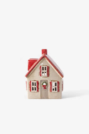 Cream ceramic tea light cottage with red shutters, red roof, and festive wreath on the door