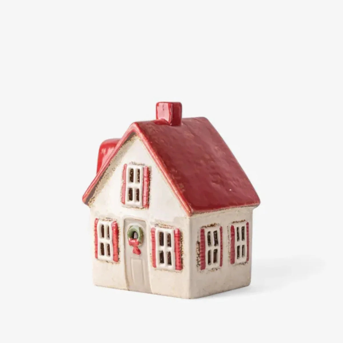 Side view of cream ceramic cottage with red shutters, red roof, and holiday wreath decor