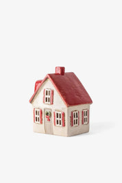 Side view of cream ceramic cottage with red shutters, red roof, and holiday wreath decor