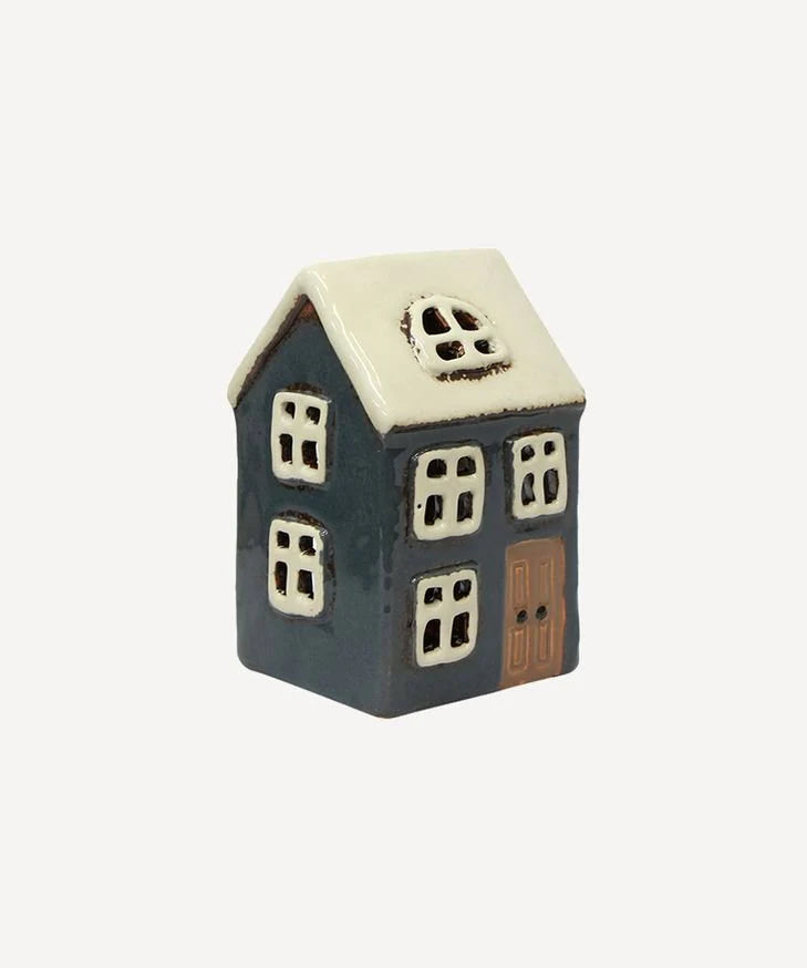 Side view of navy ceramic tea light house with white roof and window cutouts