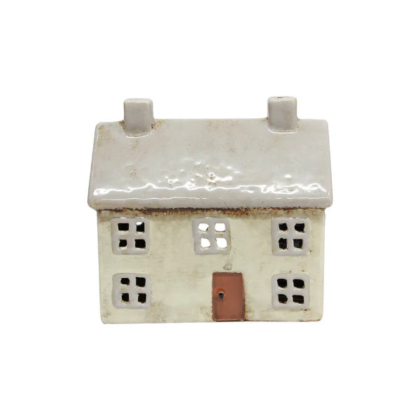 Light grey ceramic tea light house with two chimneys, square cut-out windows, and a brown front door