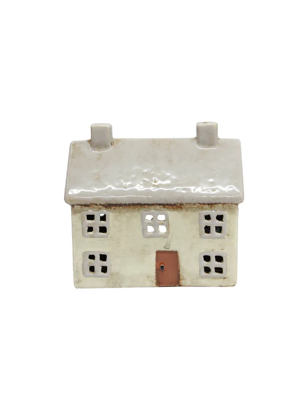 Light grey ceramic tea light house with two chimneys, square cut-out windows, and a brown front door