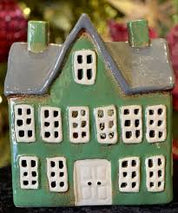 Front view of green ceramic tea light manor house with grey gabled roof, white door, and multiple square cut-out windows
