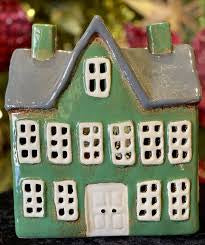 Front view of green ceramic tea light manor house with grey gabled roof, white door, and multiple square cut-out windows