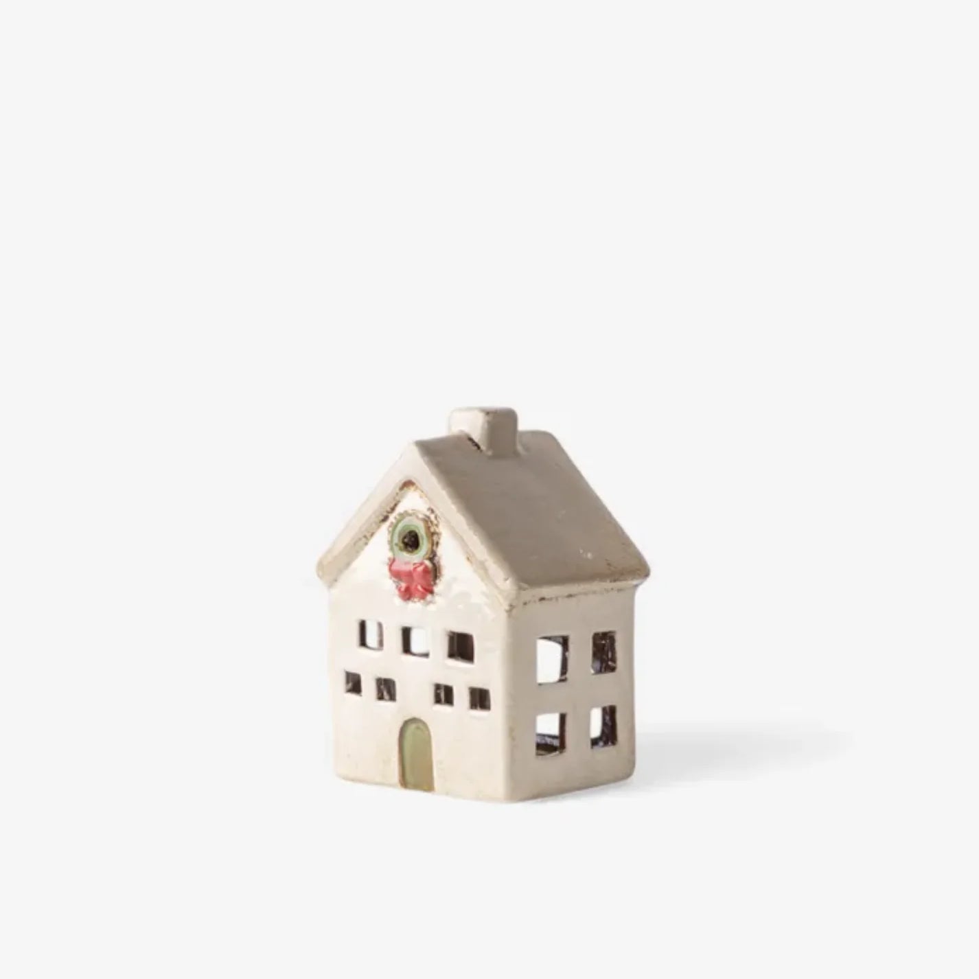 Side view of ceramic Christmas tea light villa in stone finish with wreath above door and cutout windows
