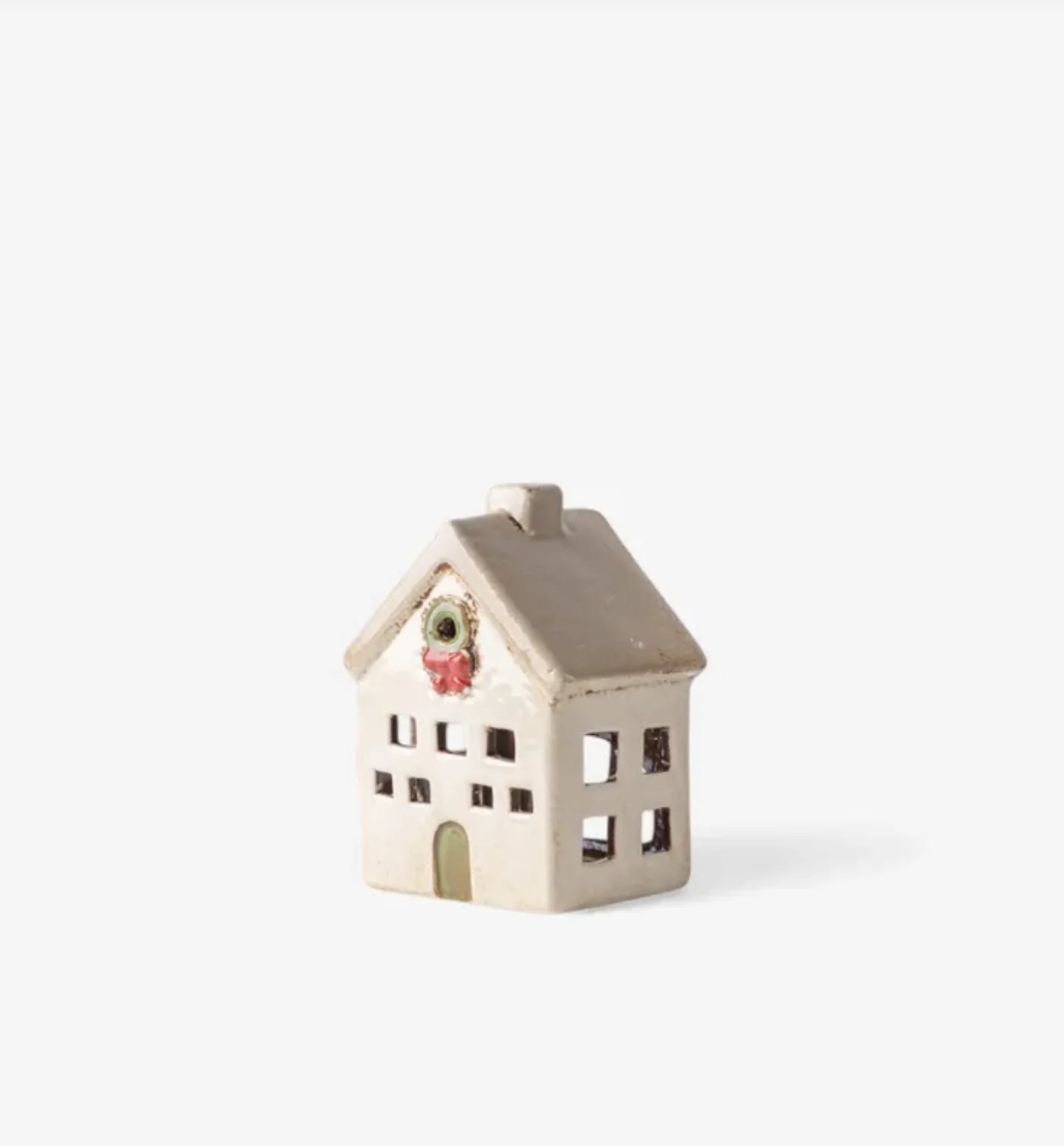 Side view of ceramic Christmas tea light villa in stone finish with wreath above door and cutout windows