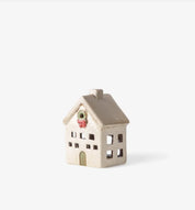 Side view of ceramic Christmas tea light villa in stone finish with wreath above door and cutout windows