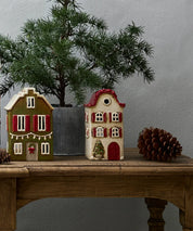 French Country ceramic Christmas tea light houses including Alsace Villa with red shutters, styled with pinecone and festive greenery.