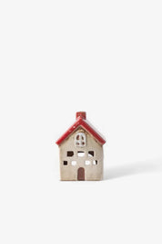 Front view of small ceramic tea light house in white with red roof and cut out windows