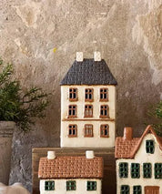 Styled display of French Country Cotswolds Country Tea Light Estate House with plants and other ceramic houses.