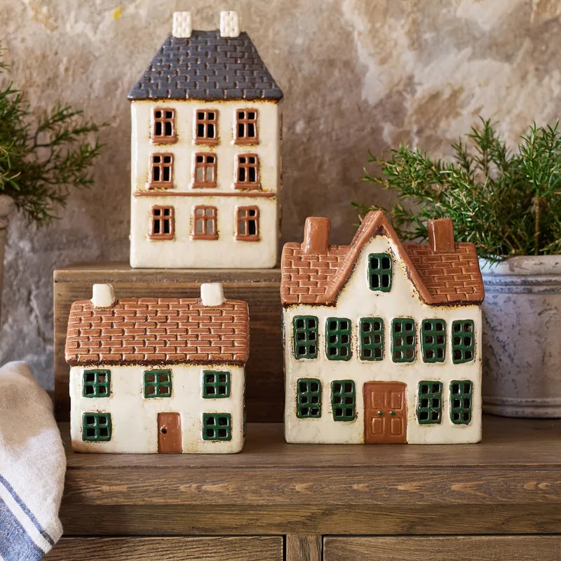 French Country ceramic tea light houses including the Cotswolds Country Manor, styled on wooden surface with greenery.