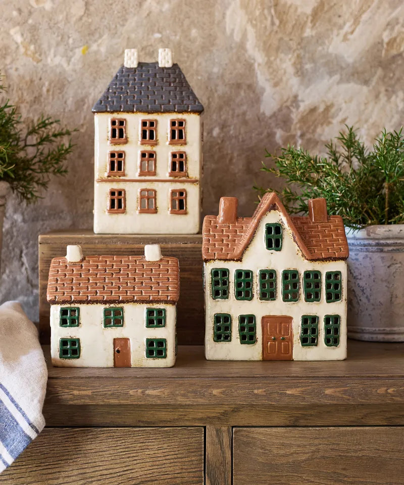 French Country ceramic tea light houses including the Cotswolds Country Manor, styled on wooden surface with greenery.
