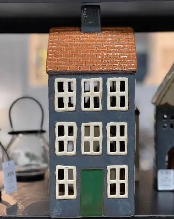 Decorative ceramic tea light chalet with navy walls, green door, and terracotta roof displayed indoors.