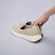 Close-up of Keds BlissWalk Loafer Eng Knit Taupe sneakers with textured knit upper and white sole, shown being held by the heel.