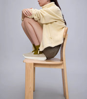 Model wearing Keds BlissWalk Loafer Eng Knit Taupe slip-on sneakers paired with socks and casual outfit, seated on a wooden chair.