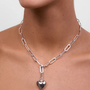 Model wearing LIBERTE Lotte Silver Heart Necklace, bold silver chain necklace with heart charm styled on neckline