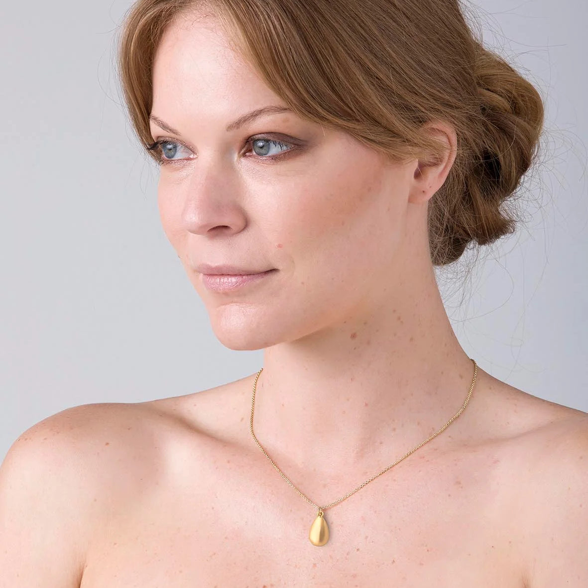 Model wearing LIBERTE Shelby Necklace in silver, elegant teardrop pendant necklace styled with strapless top