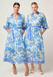 Two models wearing ONCE WAS Carmen Silk Cotton Maxi Dress in Azure Mosaic, styled with tie belts and blue floral pattern.