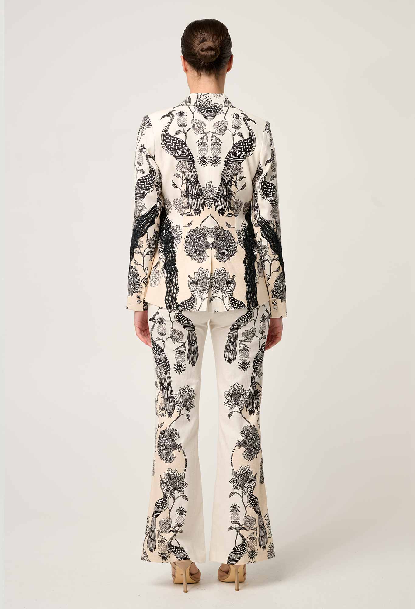 Back view of cream printed blazer with black bird and floral pattern paired with matching trousers