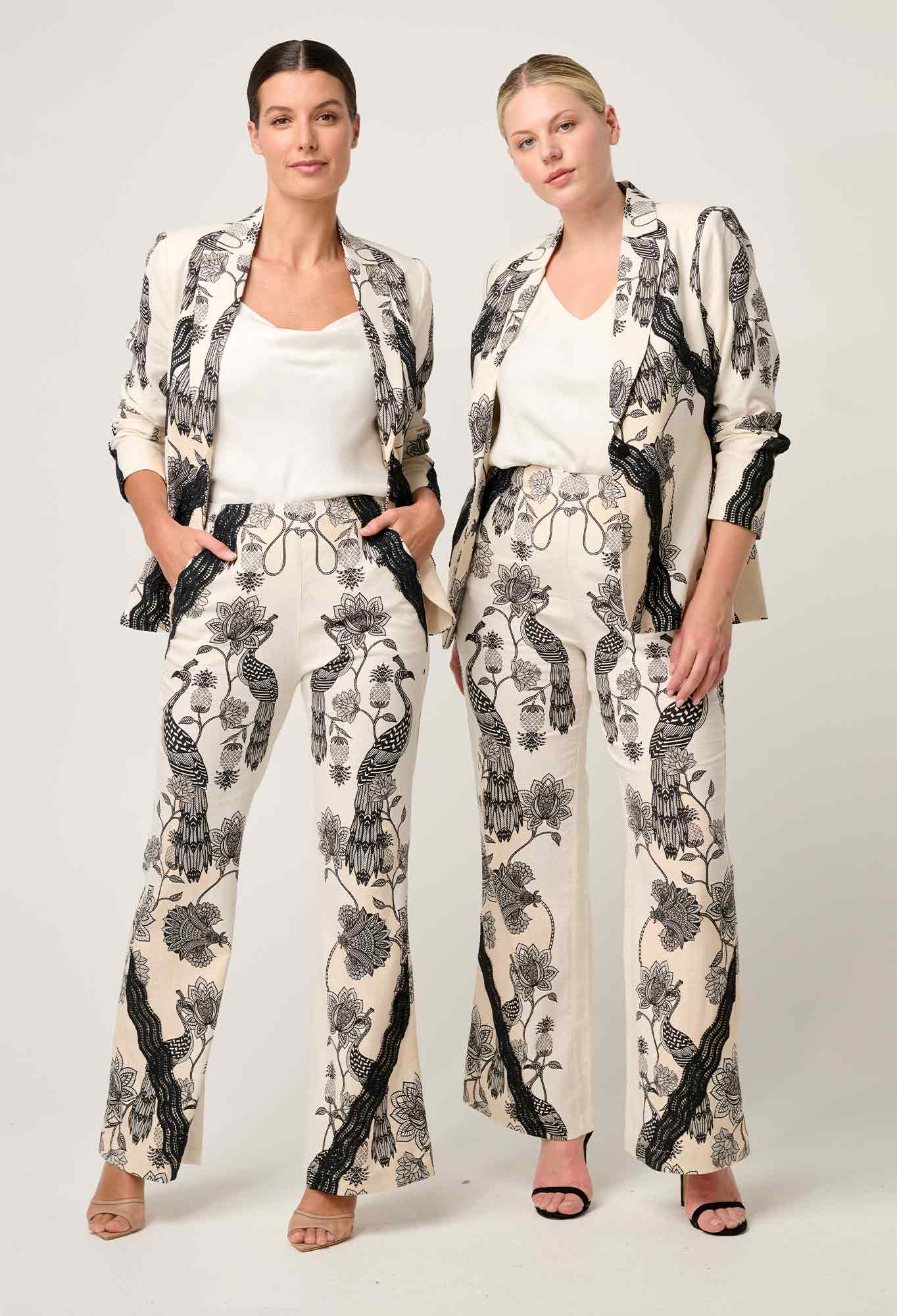 Two women modeling cream and black printed blazer and trouser set with lace contrast detail