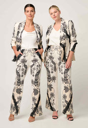 Two women modeling cream and black printed blazer and trouser set with lace contrast detail