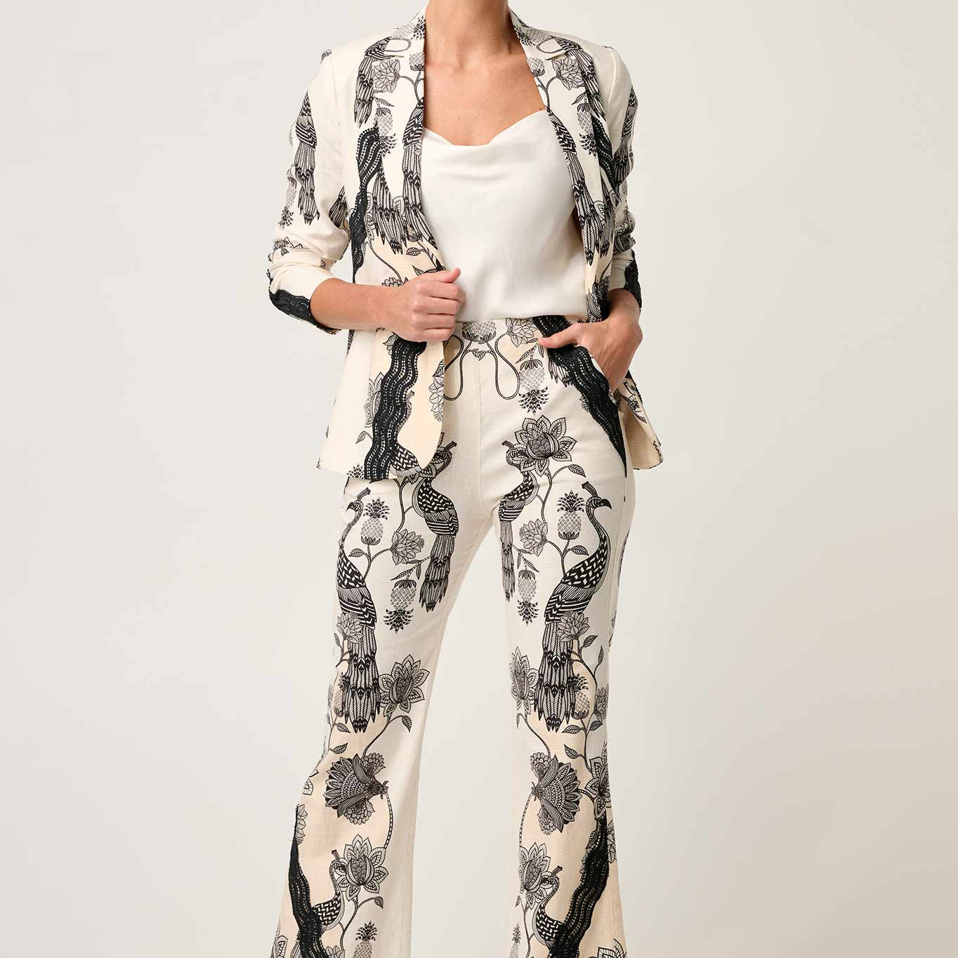 Woman modeling cream blazer with black floral bird print and matching trousers front view