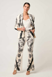 Woman modeling cream blazer with black floral bird print and matching trousers front view
