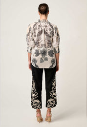 Back view of cream blouse with black bird and floral print styled with black embroidered trousers