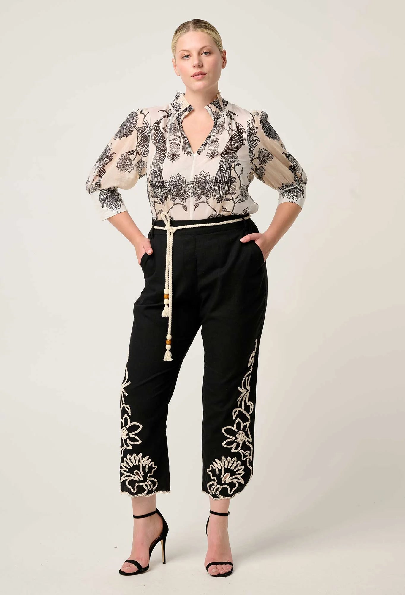 Woman modeling cream printed blouse with three quarter sleeves styled with black embroidered pants