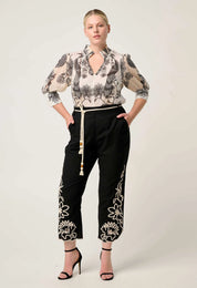 Woman modeling cream printed blouse with three quarter sleeves styled with black embroidered pants