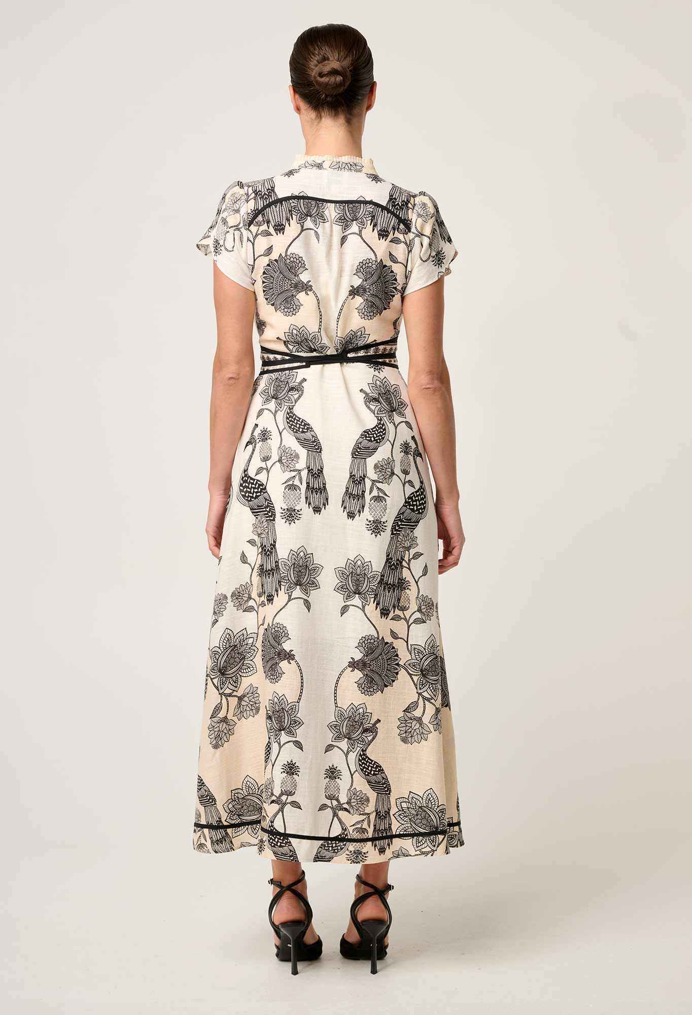 Back view of cream and black printed maxi dress showing bird and floral pattern with belt detail