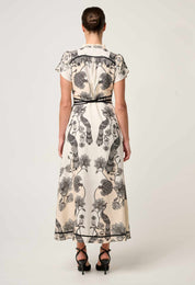 Back view of cream and black printed maxi dress showing bird and floral pattern with belt detail
