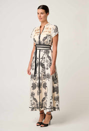 Side angled view of cream and black printed maxi dress with diamond smock yoke and waist belt