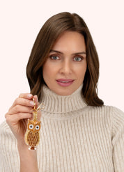 Model holding POWDER beaded golden owl keyring
